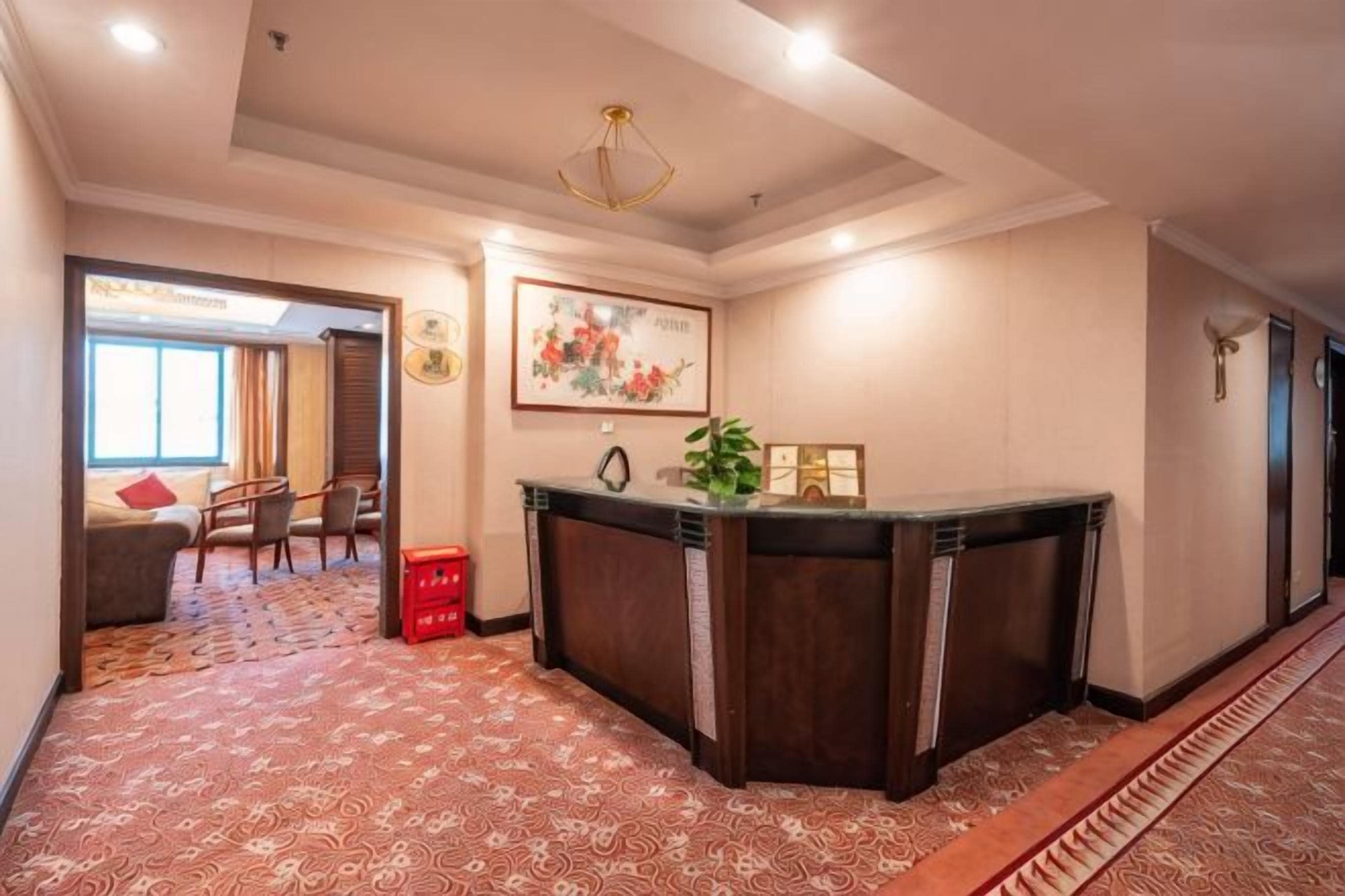 A hotel lobby with a reception desk, a dining area, and a patterned carpet.