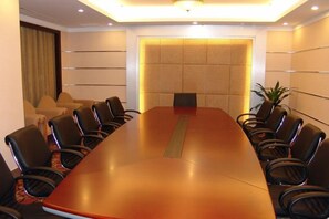 A conference room with a long table and chairs, a plant, and a large window. - Royal Prince Hotel (Quanzhou)