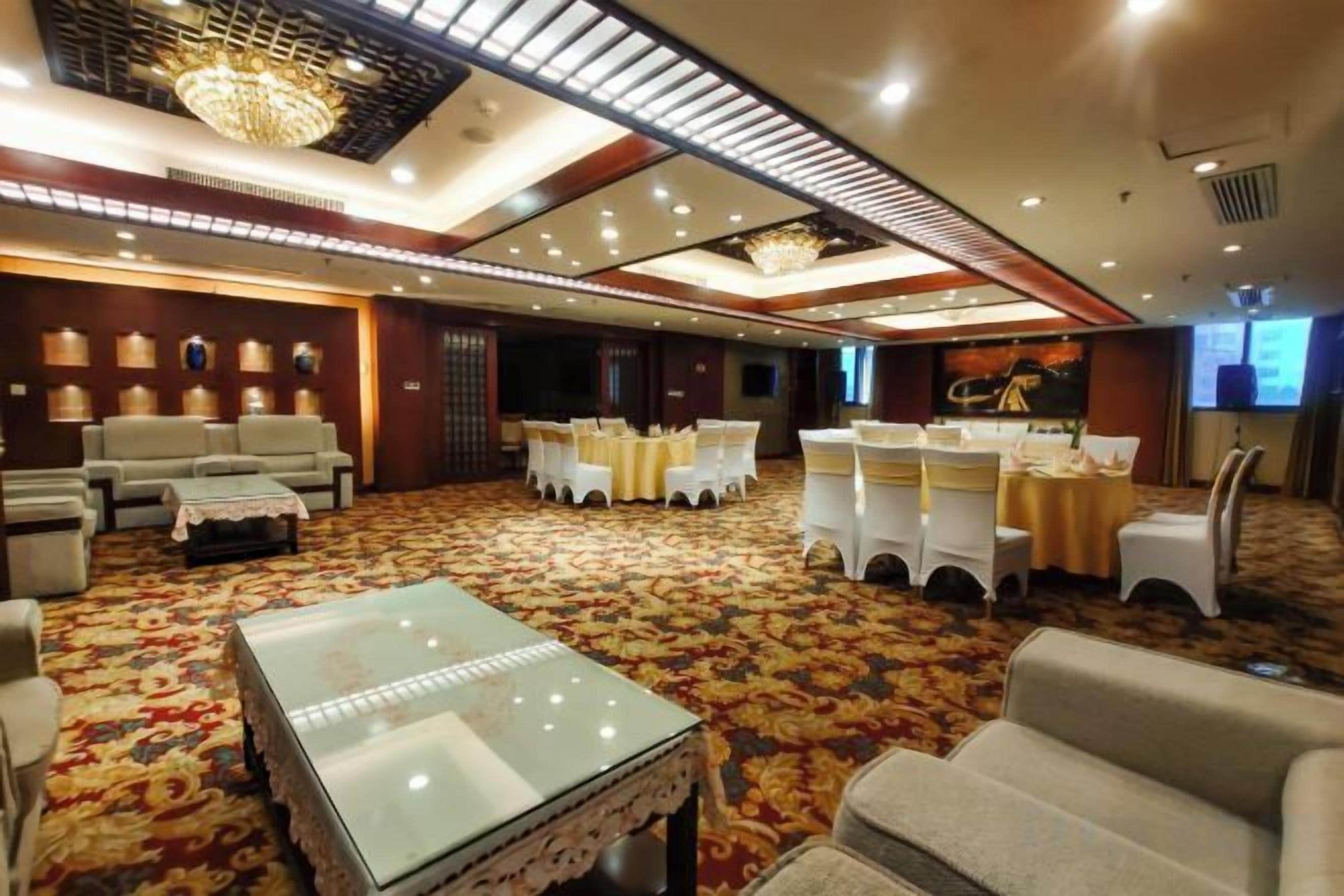Una habitación amplia con alfombra estampada, una mesa de centro de vidrio y una zona de estar con sofás y sillones.