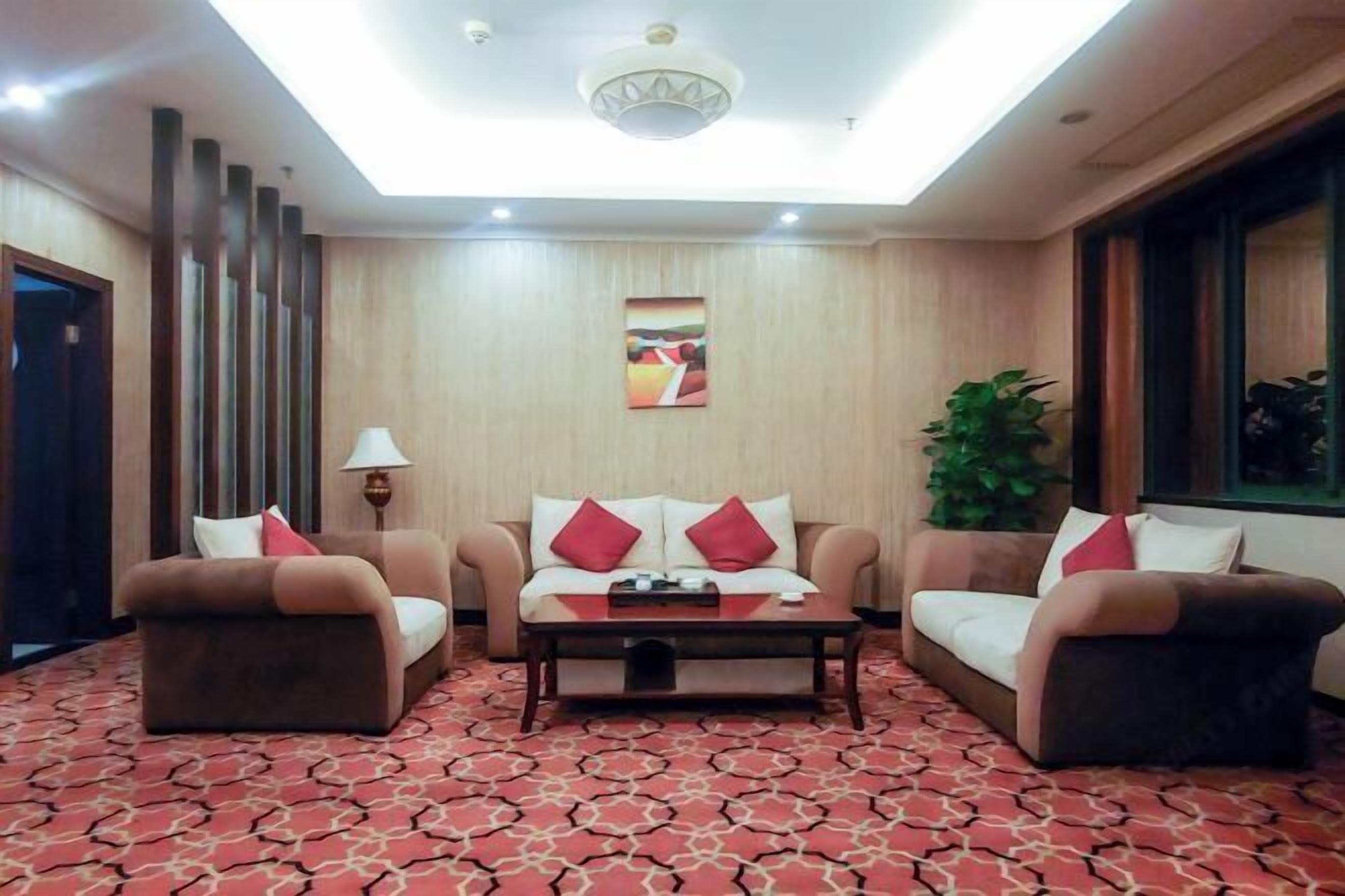 Habitación de hotel con sofá, mesa de centro, lámpara y un cuadro en la pared.