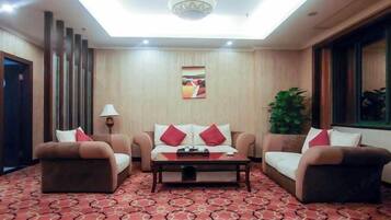 Habitación de hotel con sofá, mesa de centro, lámpara y un cuadro en la pared.