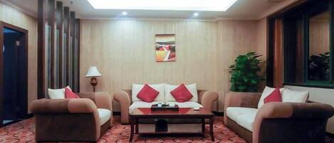 Une chambre d’hôtel avec un canapé, une table basse, une lampe et un tableau au mur.