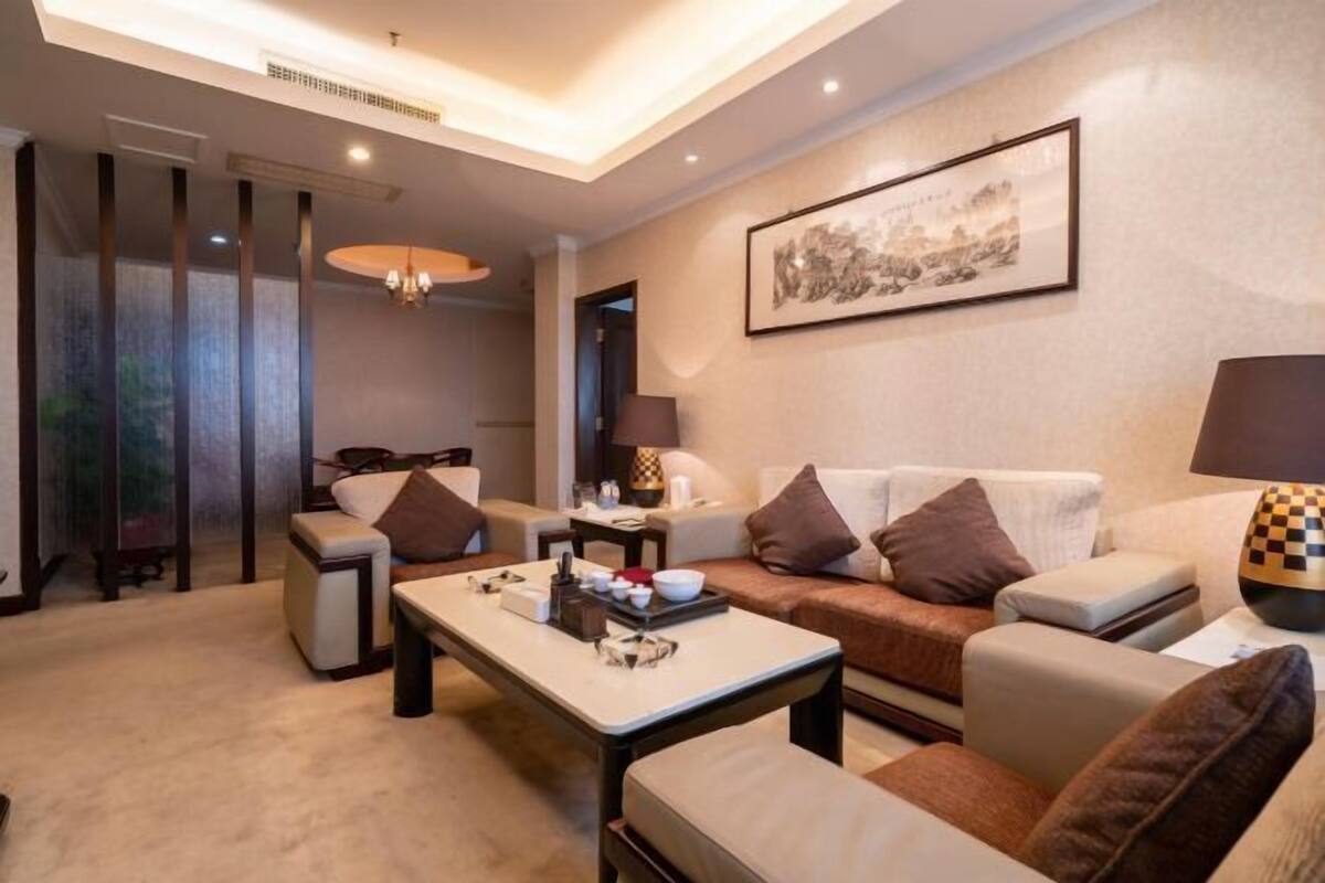 A modern living room with a sofa, armchairs, a coffee table, and a lamp.