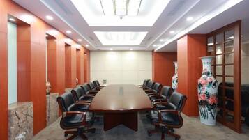 Un salón de conferencias con una gran mesa ovalada, sillas de cuero y un jarrón decorativo.