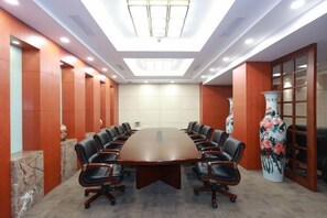 A conference room with a large oval table, leather chairs, and a decorative vase. - Yueda International Hotel (Yancheng)