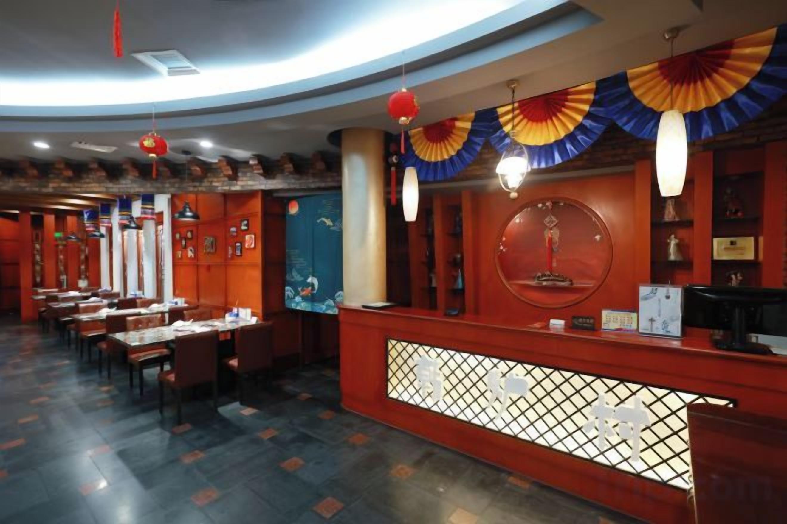 A restaurant interior with a reception desk, dining tables, and chairs.