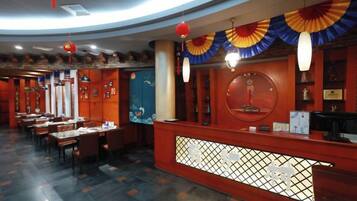 A restaurant interior with a reception desk, dining tables, and chairs.