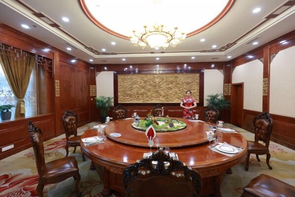 A conference room with a round table, chairs, and a chandelier.
