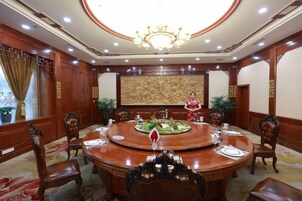 Un salón de conferencias con una mesa redonda, sillas y una araña.