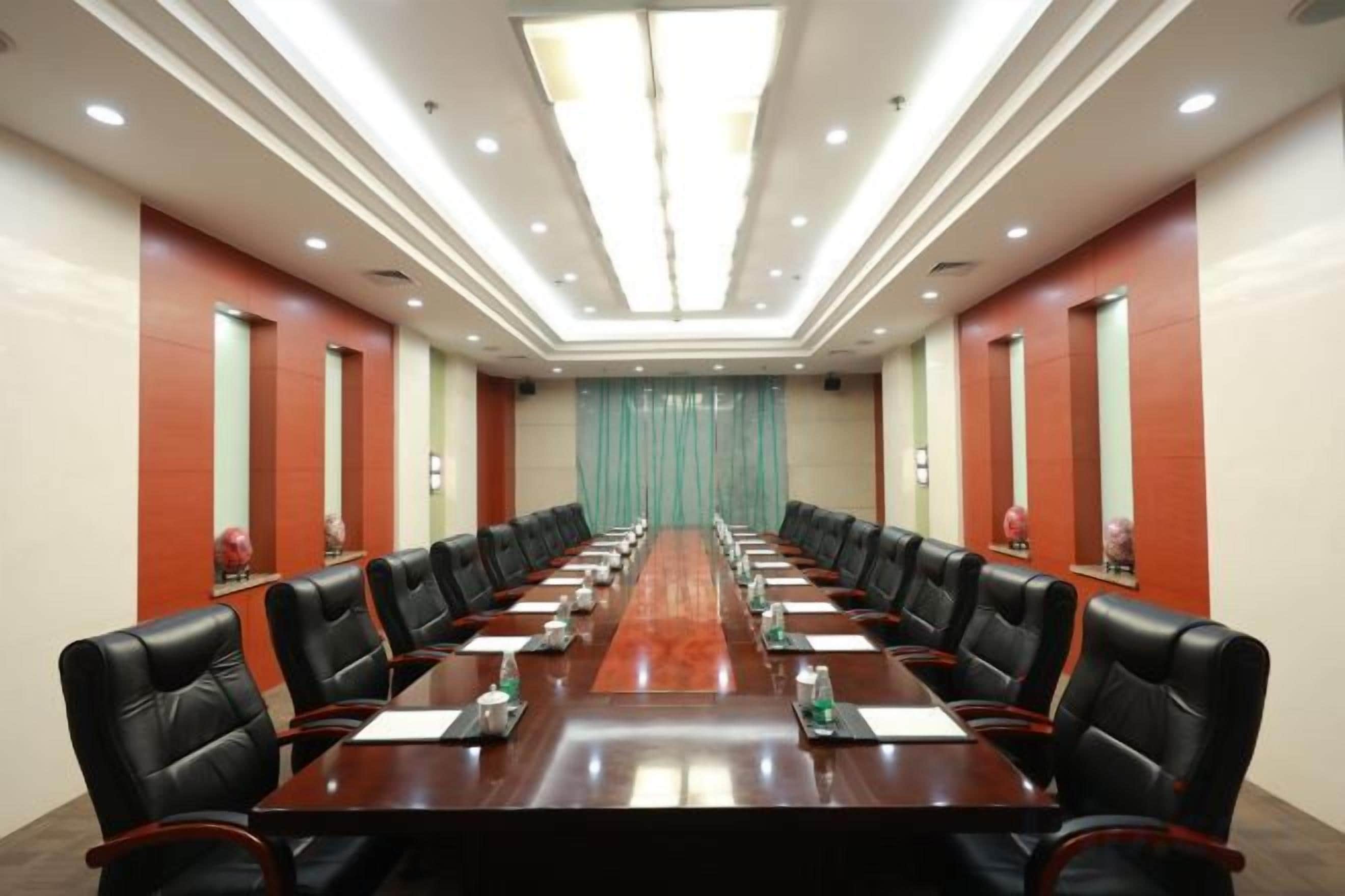 A conference room with a long table, multiple chairs, and a curtain backdrop.