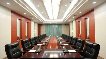 A conference room with a long table, multiple chairs, and a curtain backdrop.