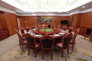 A conference room with a round table, chairs, a chandelier, a painting, and a television. - Yueda International Hotel (Yancheng)
