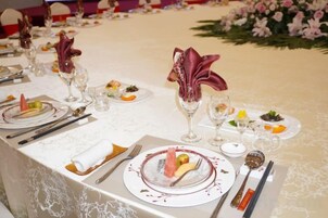 Una mesa dispuesta con cubertería elegante, platos y una decoración central.