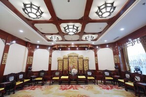 A conference room with a high ceiling, ornate wall decorations, and a central decorative panel. - Yueda International Hotel (Yancheng)