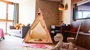 A cozy living room with a play tent, a rocking horse, and a flat-screen TV mounted on the wall. - Tarshan Hotel (WEIHAI)