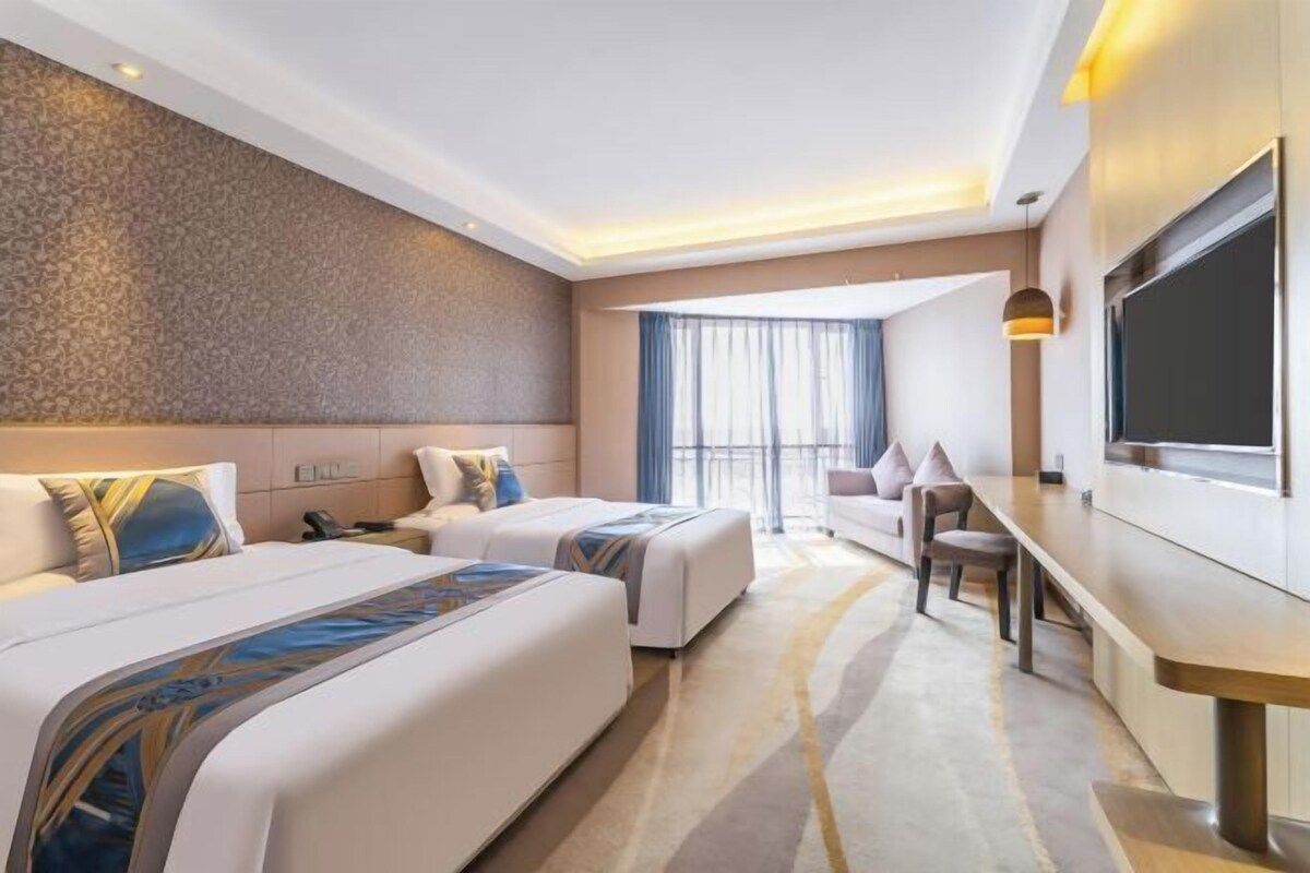 Een hotelkamer met twee bedden, een bank, een televisie en een bureau.