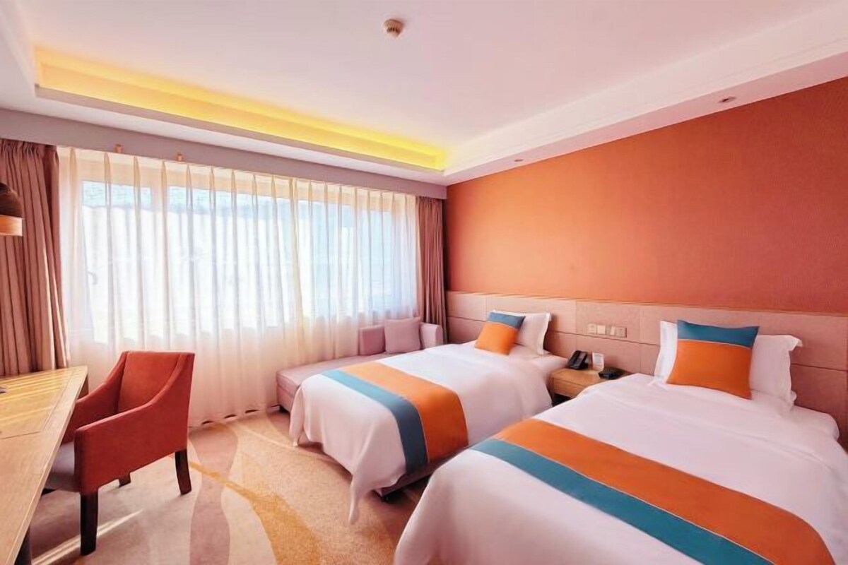 A hotel room with two beds, a desk, and a chair.