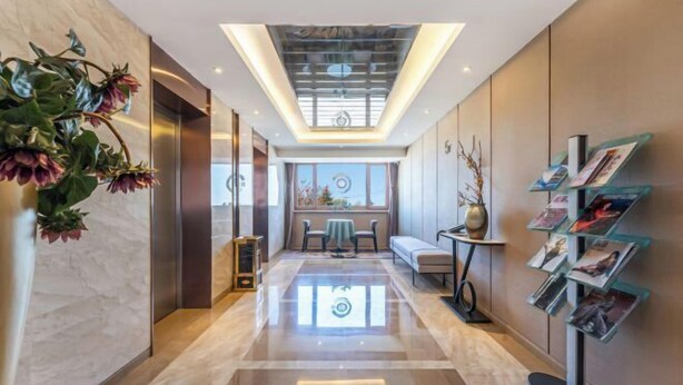 A modern hotel lobby with a central seating area, a reception desk, and a wall-mounted photo display. - Tarshan Hotel (WEIHAI)