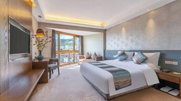 Una habitación de hotel moderna con una cama grande, televisor, escritorio y balcón con vistas.