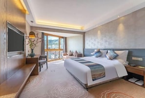 A modern hotel room with a large bed, a TV, a desk, and a balcony with a view. - Tarshan Hotel (WEIHAI)