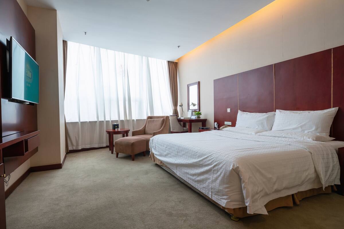 Een hotelkamer met een groot bed, een televisie, een bureau en een stoel.