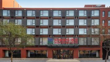 Un hôtel à plusieurs étages, doté d’une façade rouge et d’une entrée centrale.