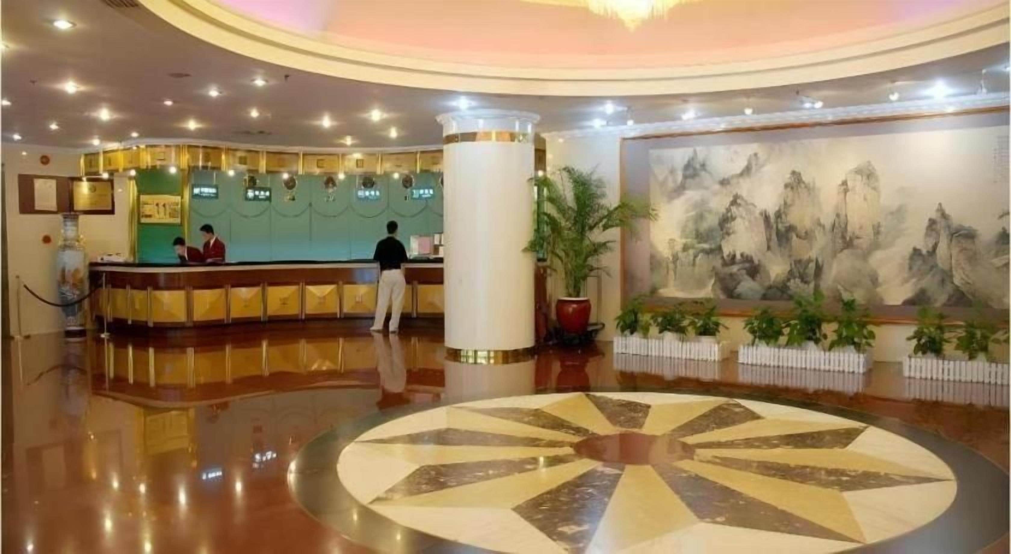 Un vestíbulo de hotel con una recepción, un diseño circular en el suelo y un cuadro en la pared.