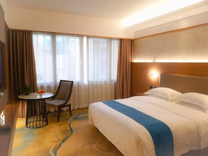 A hotel room with a bed, a chair, a small table with a plant and fruit, and a window with curtains. - Shenzhen Lotus Hotel (SHENZHEN)