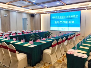 A conference room with multiple tables, chairs, and a large screen displaying text. - Shenzhen Lotus Hotel (SHENZHEN)