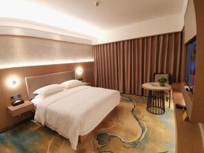 A hotel room with a large bed, bedside tables, a small table with a plant, and a view of the city. - Shenzhen Lotus Hotel (SHENZHEN)