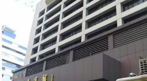 A multi-story building with a modern architectural design, featuring a series of balconies and a prominent entrance with signage. - Shenzhen Lotus Hotel (SHENZHEN)