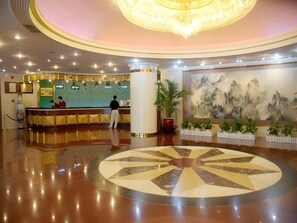 A hotel lobby with a reception desk, a large chandelier, a circular mosaic floor, and a traditional painting on the wall. - Shenzhen Lotus Hotel (SHENZHEN)