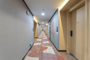 A hotel corridor with doors on the right, a patterned carpet, and a light-colored floor. - Nanyuan Ejiaplus Hotel (Ninghai Xizi International) (NINGHAI)