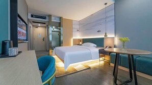 A hotel room with a bed, bedside table, chair, and a small round table with a vase. - Nanyuan Ejiaplus Hotel (Ninghai Xizi International) (NINGHAI)