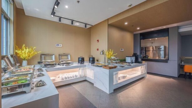 A modern breakfast buffet area with stainless steel appliances, a marble counter, and yellow flowers. - Nanyuan Ejiaplus Hotel (Ninghai Xizi International) (NINGHAI)