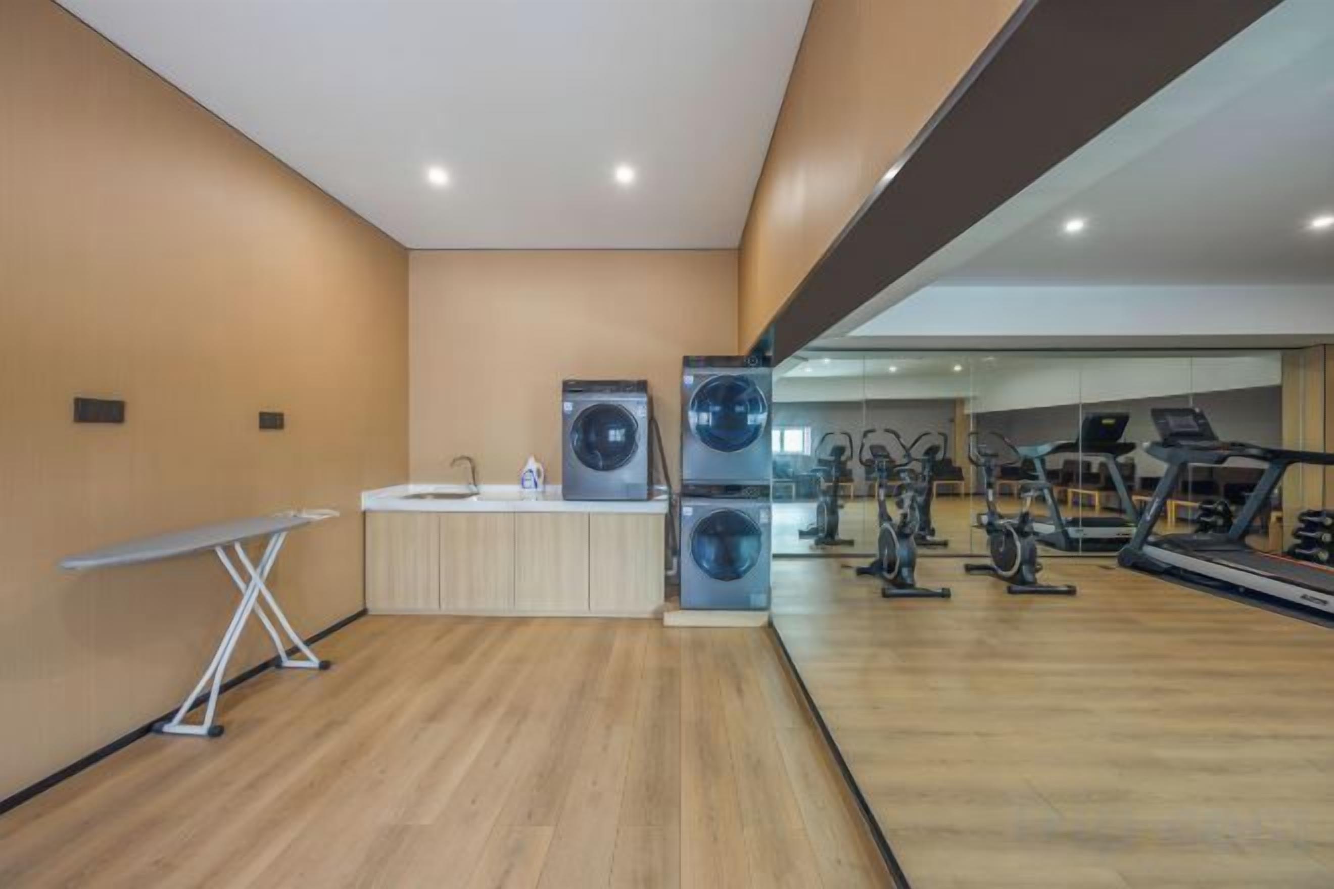 Une salle de sport équipée de matériel d’exercice, d’un espace pour se laver et d’un miroir qui reflète l’ensemble de la pièce.