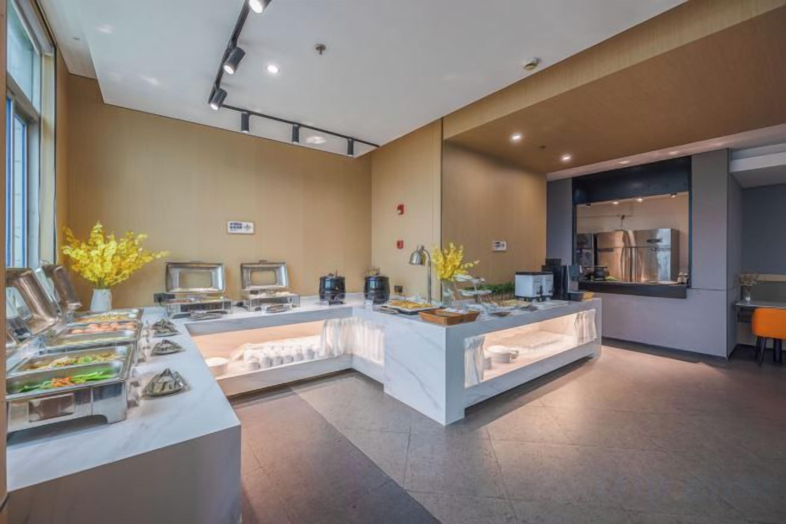 Un espace buffet avec plusieurs postes de service pour les différents plats, une machine à café et un coin salon offrant une vue sur la cuisine.