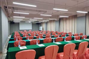 A conference room with rows of tables and chairs, a projector screen, and a whiteboard. - South Garden Hotel (Chongqing)