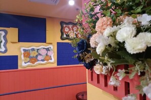 A room with a colorful wall, a floral arrangement, and a red bench. - South Garden Hotel (Chongqing)