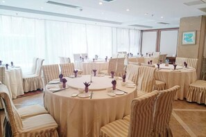 A conference room with round tables and chairs, large windows with sheer curtains, and a framed picture on the wall. - South Garden Hotel (Chongqing)