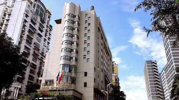 A multi-story hotel with a curved facade, multiple balconies, and a flag on the top.