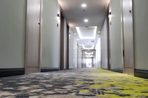 A hotel corridor with a patterned carpet, doors on both sides, and a ceiling with recessed lighting. - South Garden Hotel (Chongqing)