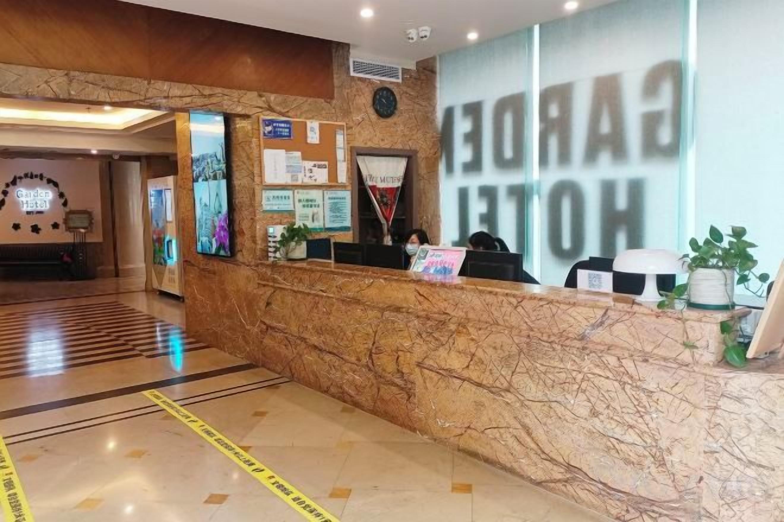 En hotellreception med en marmorskiva, en klocka och ett stort fönster där hotellets namn visas.