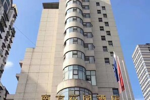 A tall building with multiple floors and windows, featuring a curved architectural design. - South Garden Hotel (Chongqing)