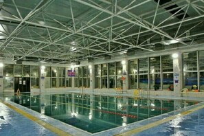 An indoor swimming pool with a high ceiling and large windows. - Haotian Holiday Hotel Beijing (Beijing)