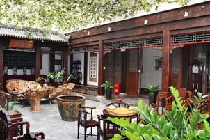 Un patio tradicional con mobiliario de madera, una fuente de piedra y plantas en macetas.