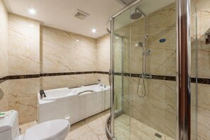 Une salle de bain avec une douche à parois de verre, une baignoire blanche et des toilettes.