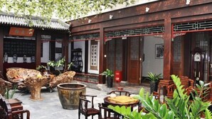 An outdoor courtyard with traditional wooden furniture, stone tables, and potted plants. - Haotian Holiday Hotel Beijing (Beijing)