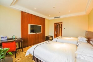 Hotellihuone, jossa on sänky, työpöytä, televisio ja ovi.