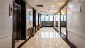 A corridor with marble flooring, an elevator, and glass doors leading to rooms. - Haotian Holiday Hotel Beijing (Beijing)